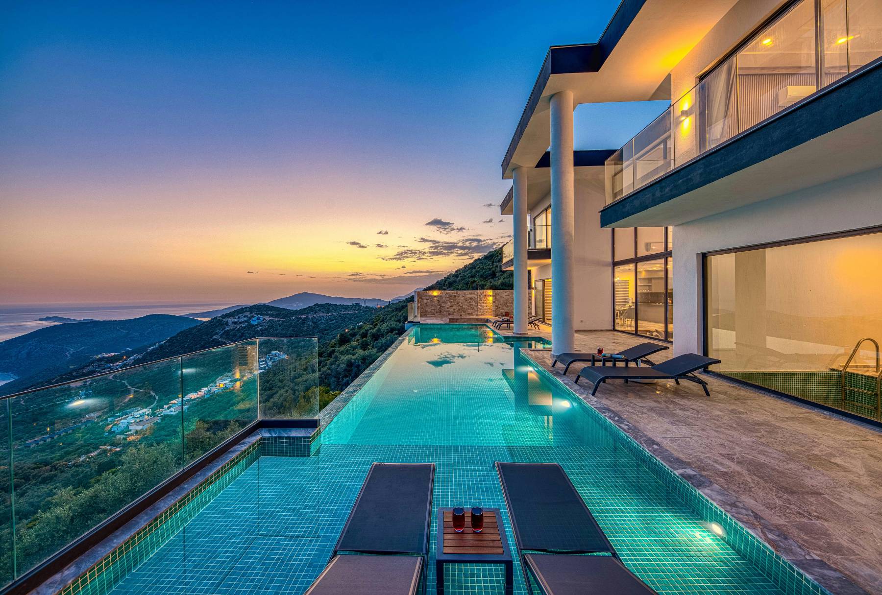 Modern bir villa ile deniz manzaralı havuz, gün batımında